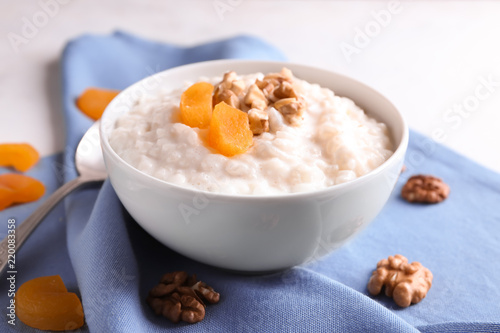 Delicious rice pudding with dried apricots and walnut in bowl on table