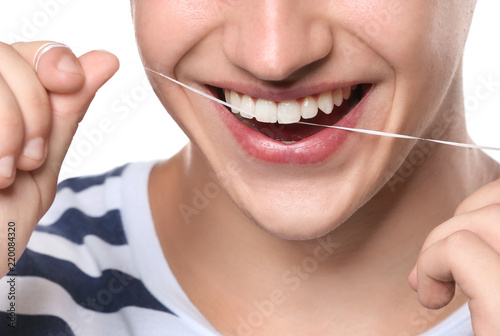 Young man flossing teeth on white background, closeup