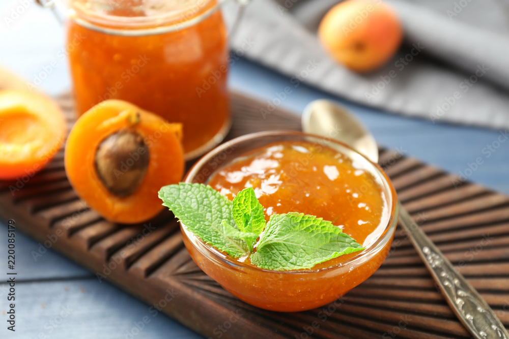 Bowl with delicious apricot jam on wooden board Bowl with delicious apricot jam on wooden board