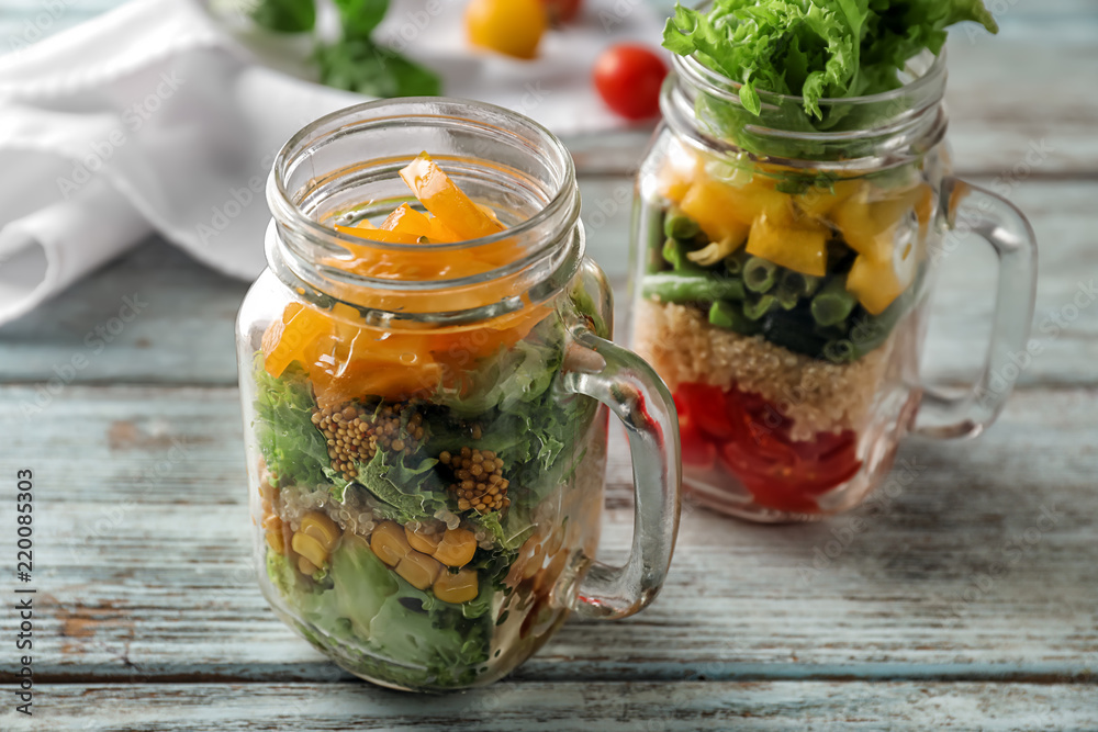 Delicious vegetable salads in mason jars on wooden table Delicious vegetable salads in mason jars on wooden table