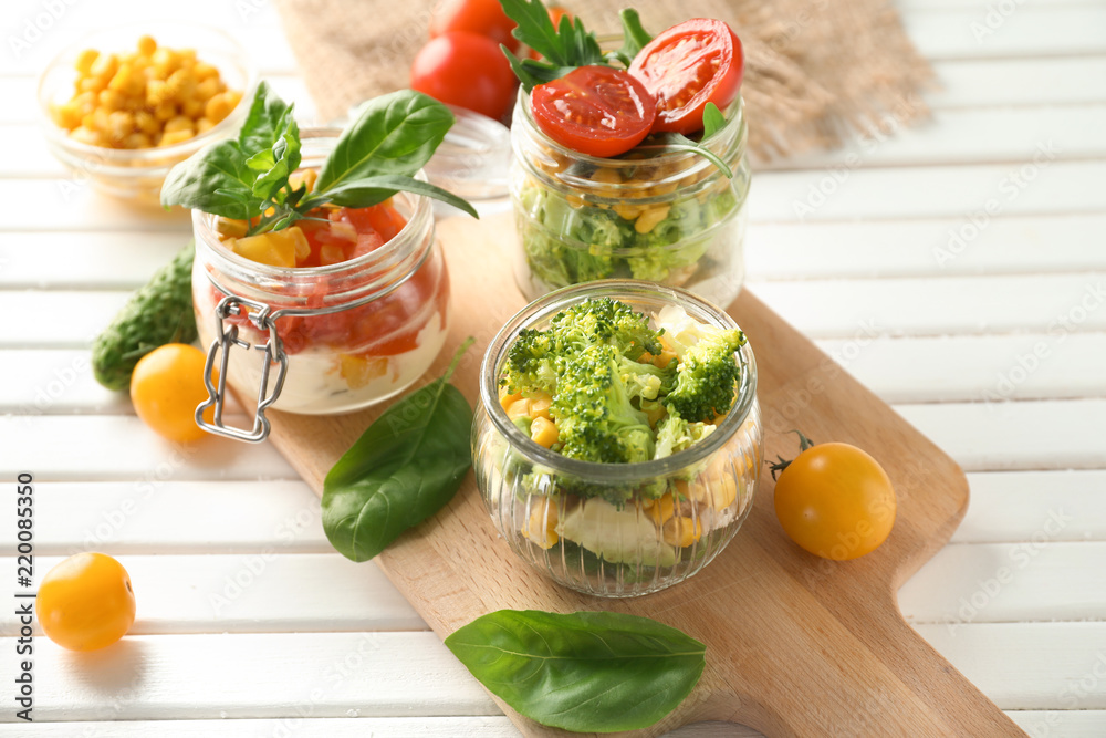 Delicious vegetable salads in mason jars on wooden board Delicious vegetable salads in mason jars on wooden board