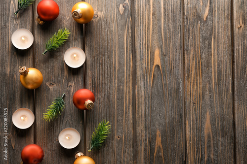 Christmas balls and burning candles on wooden background