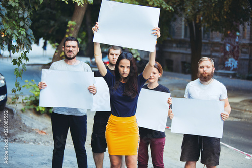 Group of protesting young people outdoors. The protest, people, demonstration, democracy, fight, rights, protesting concept. The caucasian men and womem holding empty posters or banners with copy photo