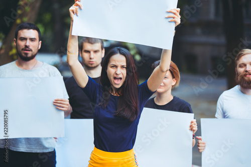Group of protesting young people outdoors. The protest, people, demonstration, democracy, fight, rights, protesting concept. The caucasian men and womem holding empty posters or banners with copy photo