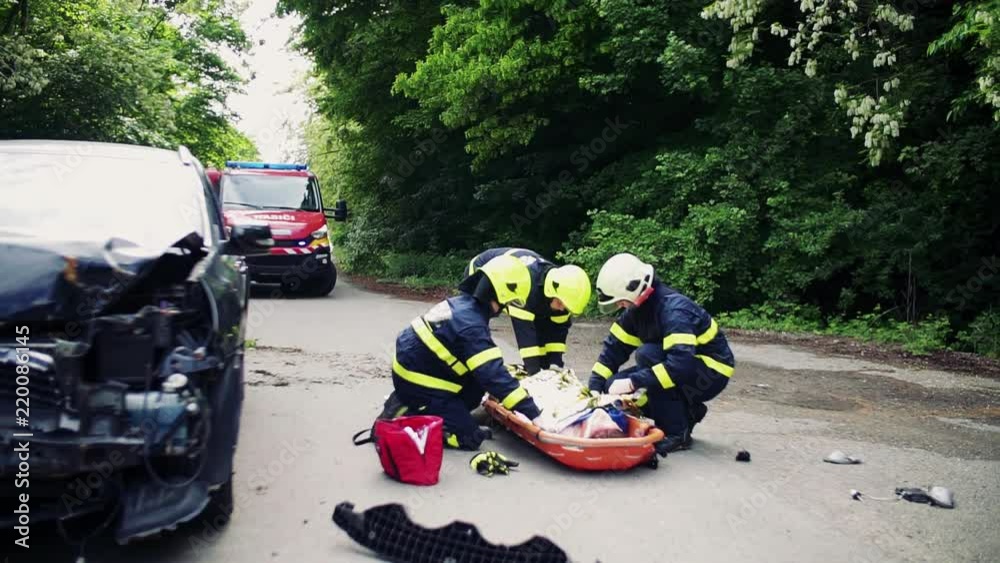 Firefighters helping a young injured woman after a car accident. Firefighters helping a young injured woman after a car accident.