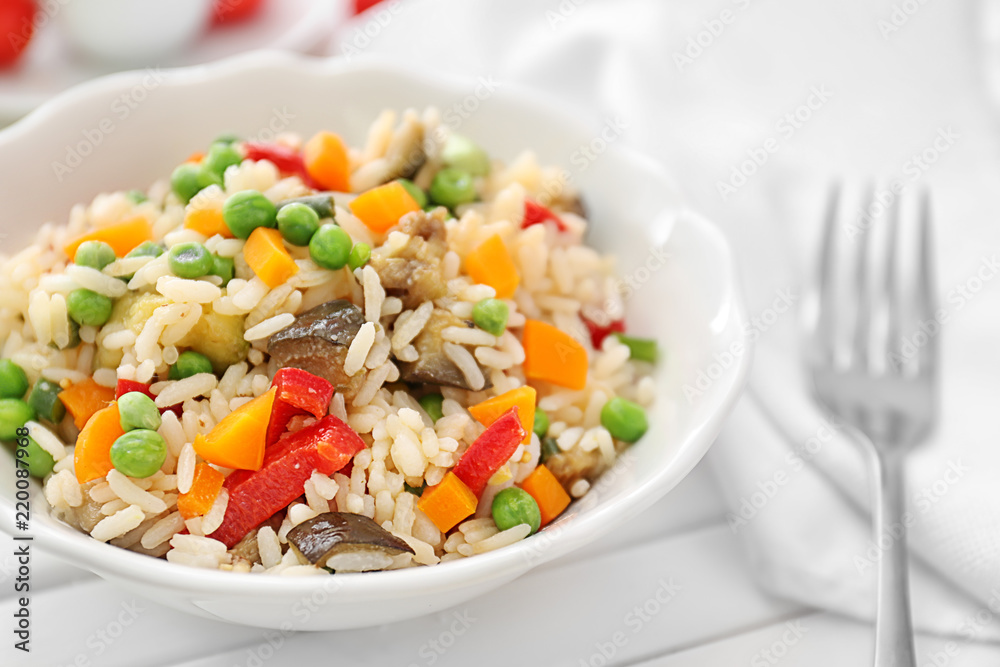 Plate with tasty boiled rice and vegetables on white table