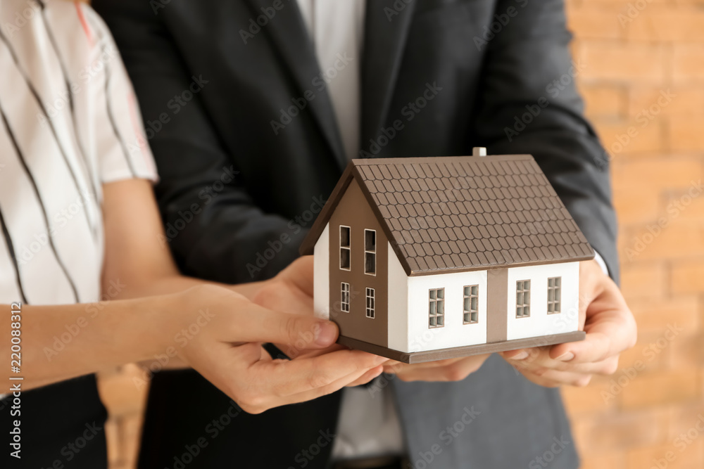 Couple with house model, closeup. Mortgage concept Couple with house model, closeup. Mortgage concept
