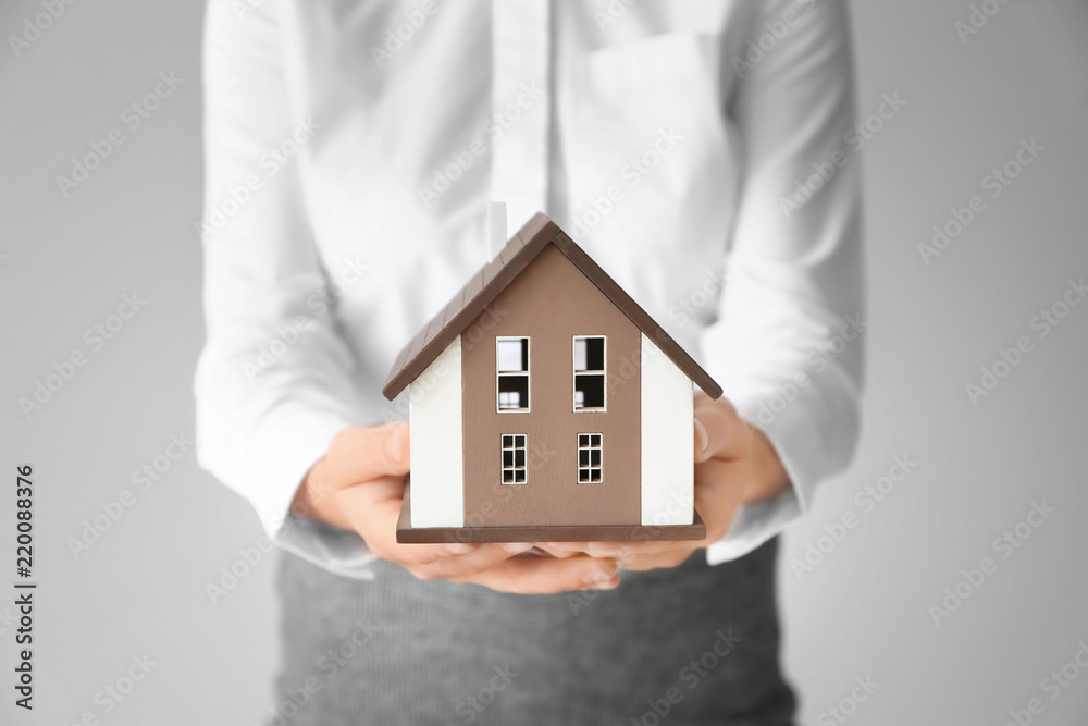 Real estate agent with house model on light background Real estate agent with house model on light background