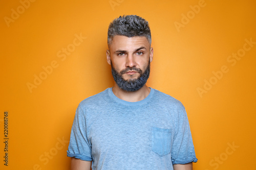 Portrait of handsome man with dyed hair and beard on color background photo