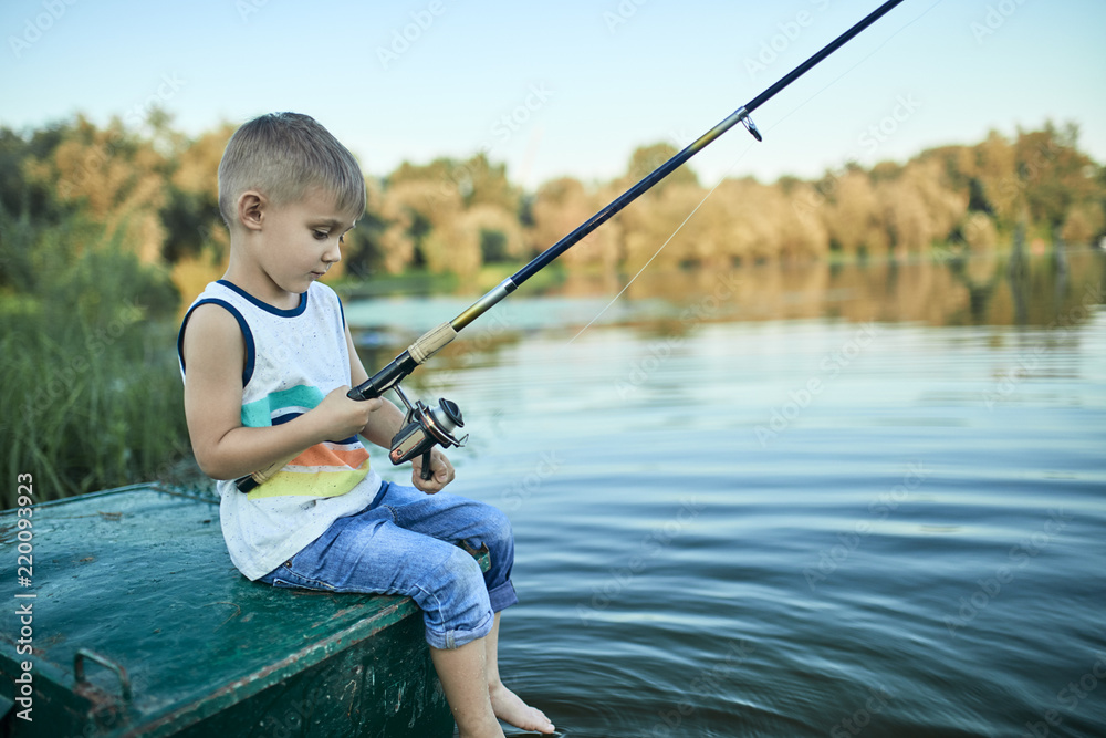Back view of little boy with fishing rod sitting on boat Back view of little boy with fishing rod sitting on boat