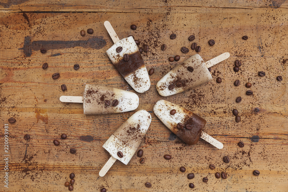 homemade Espresso Macchiato and Latte Macchiato ice lollies with coffee beans on wooden