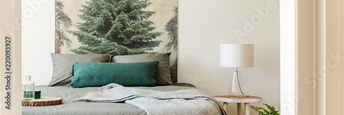 Tableau sur toile Real photo of bedside table with glass lamp standing by the double bed with grey