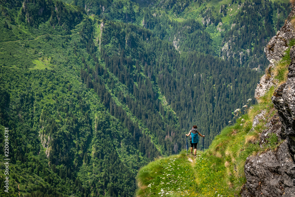 Female traveler with backpack hiking mountain trail and admiring views of Swiss Alps in Val de Bagnes area, Switzerland.