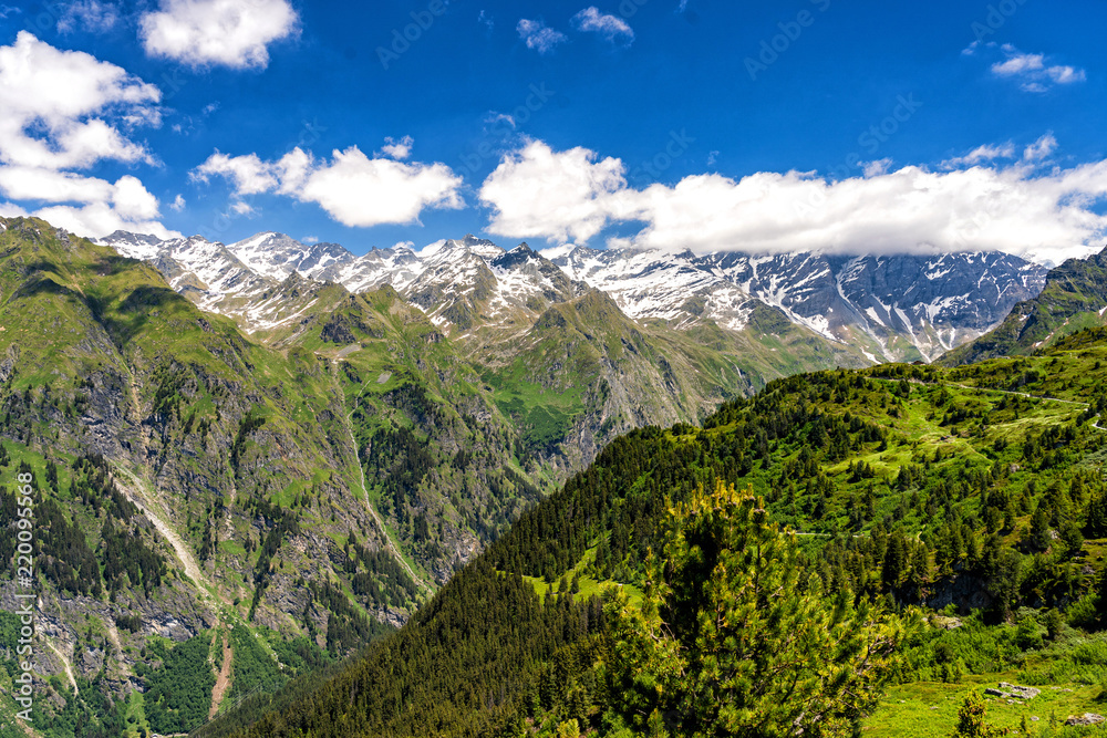Obraz premium Scenic view of beautiful landscape in Swiss Alps. Fresh green meadows and snow-capped mountain tops in the background in springtime, Switzerland.