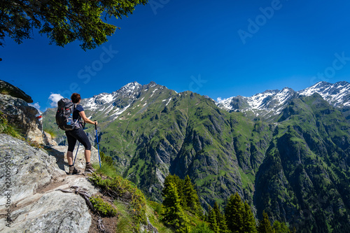 Female traveler with backpack hiking mountain trail and admiring views of Swiss Alps in Val de Bagnes area, Switzerland. © 1tomm