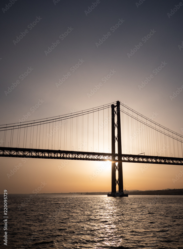 25 April Bridge silhouette, Lisbon, Portugal. Sunset view of the landmark suspension bridge crossing the Tagus River.