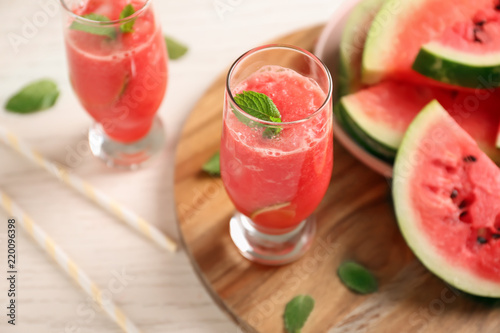 Glass with fresh smoothie and watermelon slices on wooden board