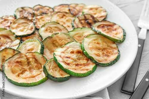 Plate with tasty grilled zucchini on light table, closeup