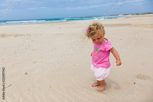 A small toddler walks and plays on the beach, St Francis, South Africa. © dougholder