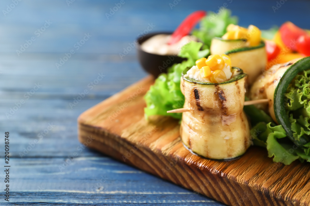 Tasty zucchini rolls with vegetables on wooden board