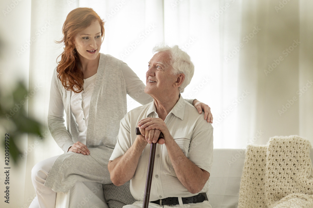 Fototapeta premium Meeting of smiling granddaughter with happy grandfather with walking stick at home