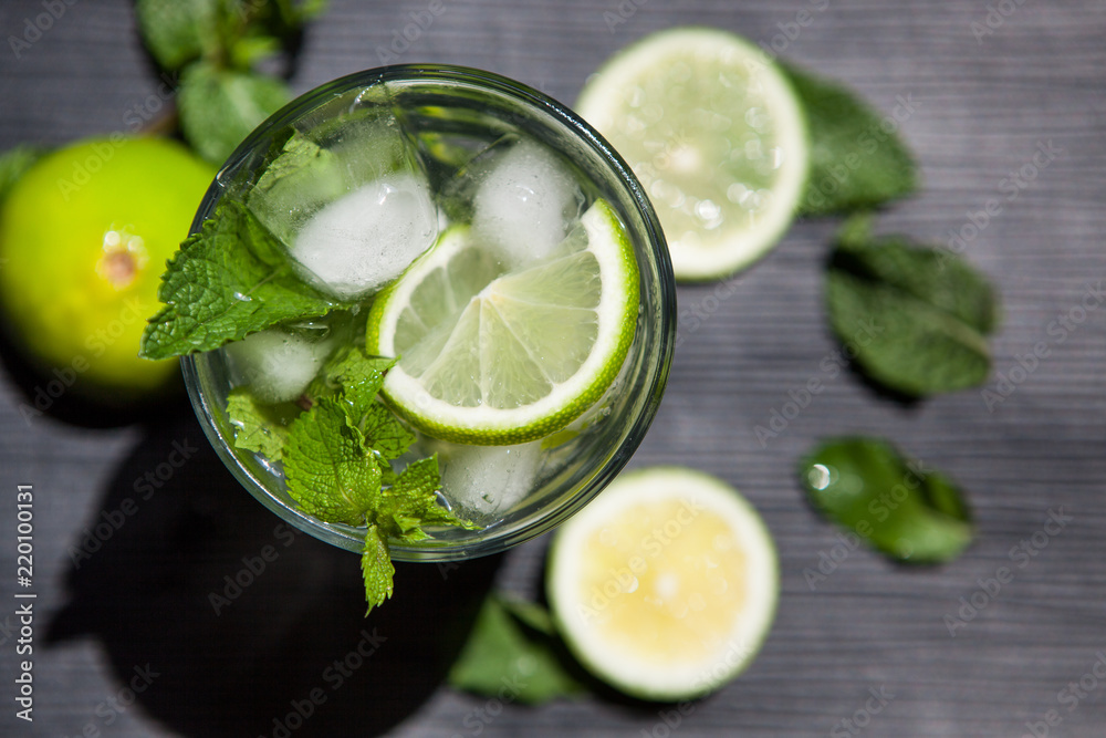 Beautiful Lemonade or Mojito coctail with lime, mint and ice, fresh drink on black table Beautiful Lemonade or Mojito coctail with lime, mint and ice, fresh drink on black table