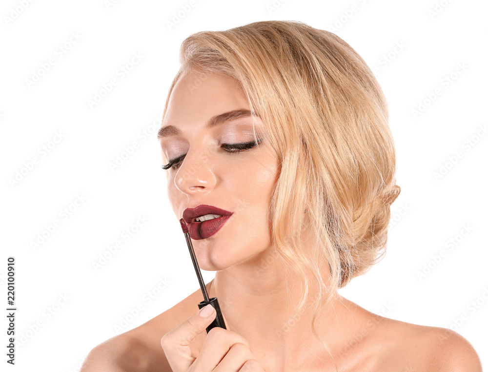 Beautiful young woman applying dark lipstick on white background Beautiful young woman applying dark lipstick on white background