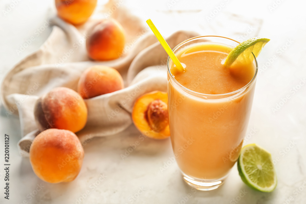 Glass with fresh peach smoothie on light table Glass with fresh peach smoothie on light table