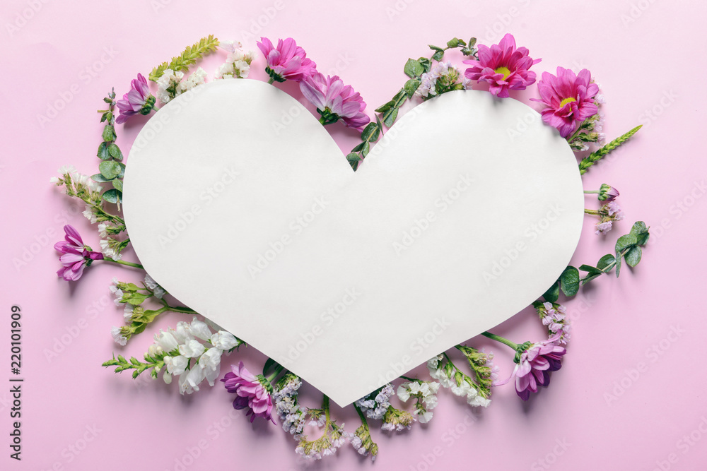 Heart shaped sheet of paper with beautiful flowers on color background