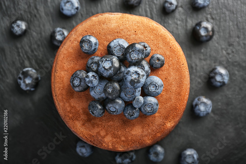 Tasty chocolate pancakes with blueberries on dark table, top view