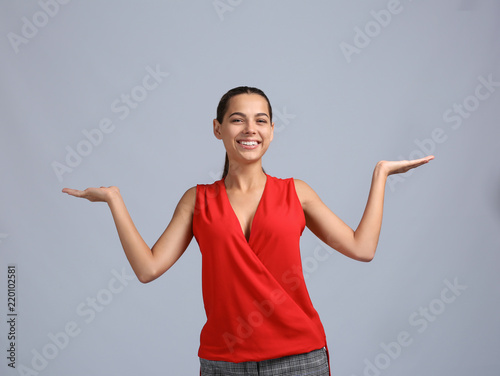 Happy young woman on grey b...