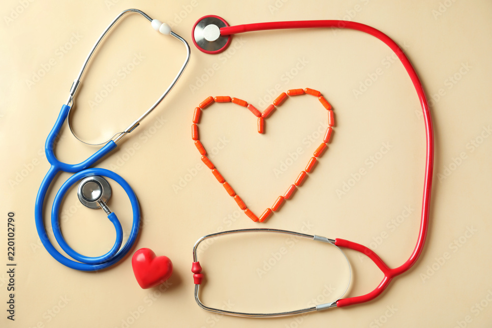 Medical stethoscopes, pills and red heart on light background. Cardiology concept Medical stethoscopes, pills and red heart on light background. Cardiology concept