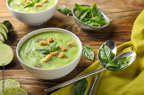 Bowl with delicious zucchini soup on wooden table