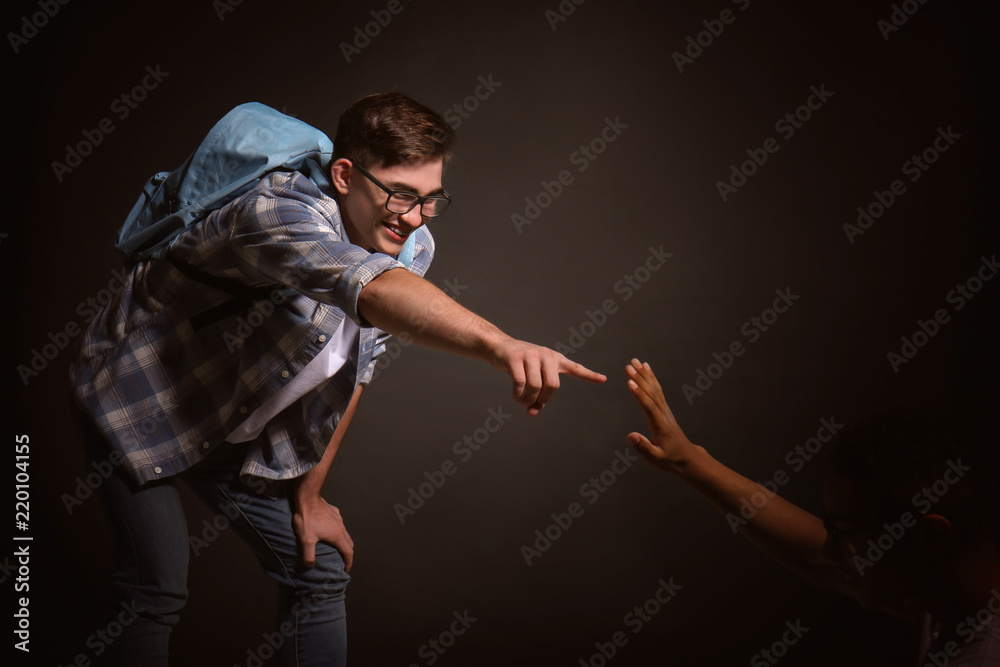 Teenager bullying African-American boy on dark background