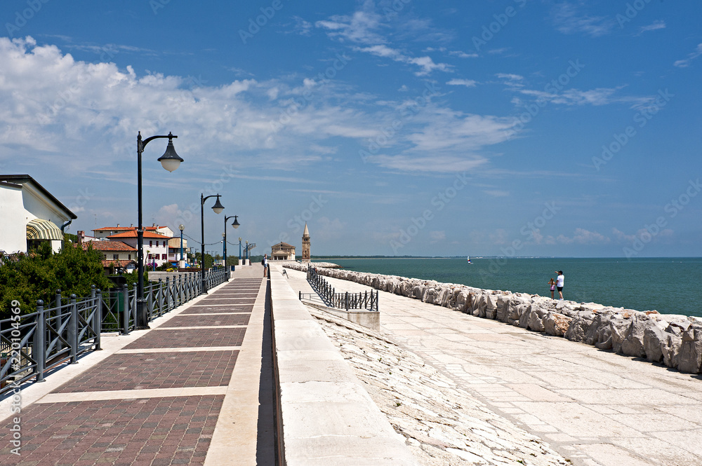 The promenade of caorle, in the background the church of the Madonna of the Angel. Veneto district, Italy.