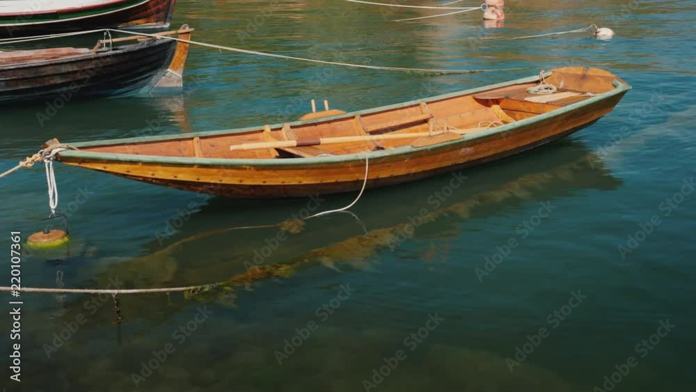 A small wooden fishing boat rocks on waves near the shore A small wooden fishing boat rocks on waves near the shore