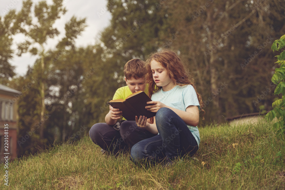 Smart little kids reading the book outdoors. Smart little kids reading the book outdoors.