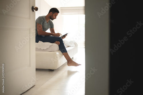 Hispanic Man Watching Movie On Tablet In Bed