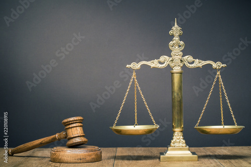 Vintage law scales and wooden gavel on the desk front dark background. Symbols of justice. Retro old style filtered photo
