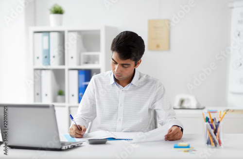 business and people concept - businessman with papers and laptop computer working at office