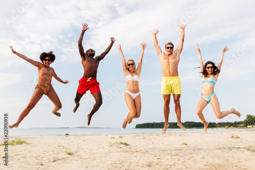 friendship  summer holidays and people concept - group of happy friends jumping and having fun on beach