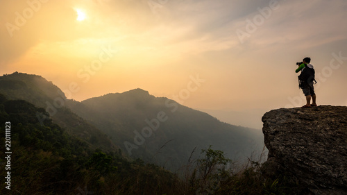 Photographer takes photos on the cliff at sunrise  leadership concept. Nature photographer in the mountain. Sunlight and sky in mountains.