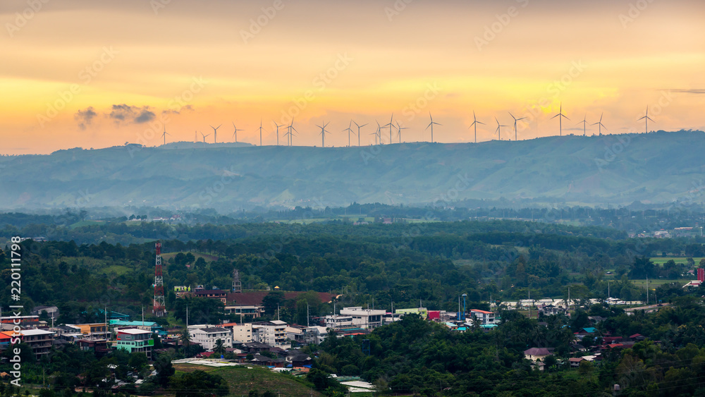 wind turbine on the mountain top. Hills and bright sky during sundown. Composition of the nature and village landscape.