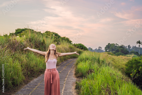 Woman Traveler Campuhan Ridge Walk or Artists Walk sacred trail, Bali island, Indonesia On the Sunset. Trail landscape palm tropical greens photo