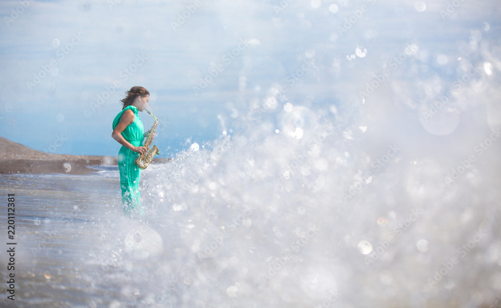 Person playing the saxophone sitting on the rocks in front of a beautiful sea Person playing the saxophone sitting on the rocks in front of a beautiful sea