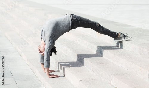 Sporty man doing advanced yoga asana outdoors
