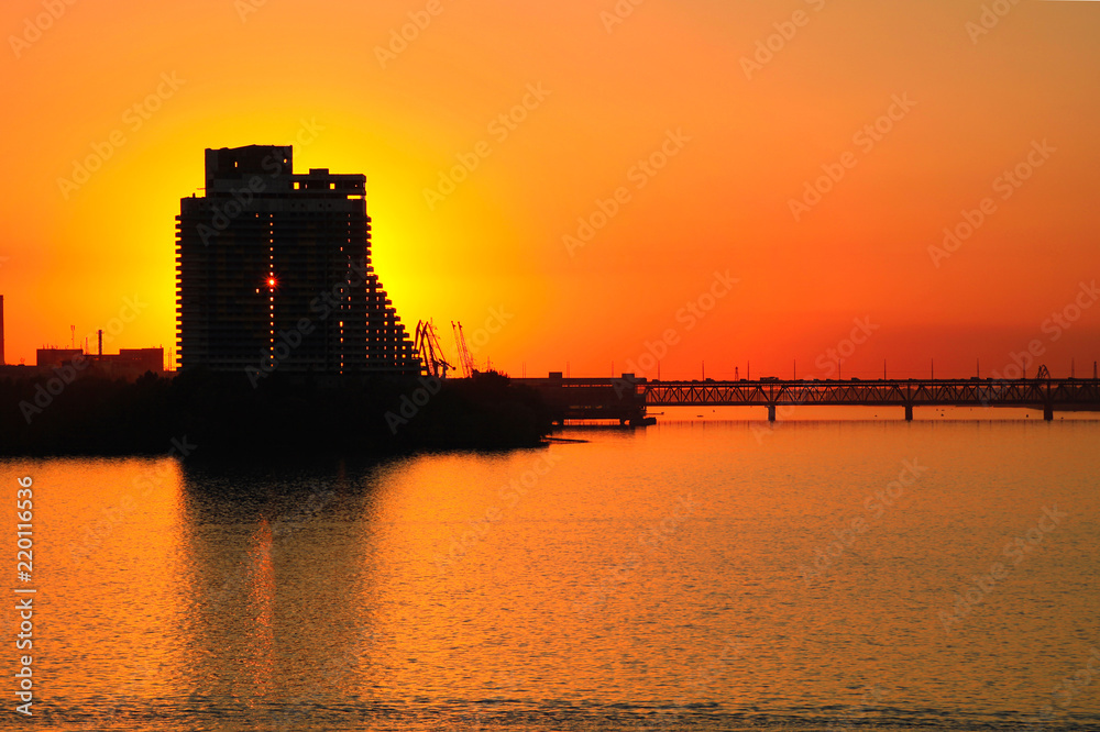 Silhouette of a skyscraper Sail and  Old bridge of an orange sunset background,  on the Dnieper River in the Dnipro city (Dnepropetrovsk, Dnepr), Ukraine. 