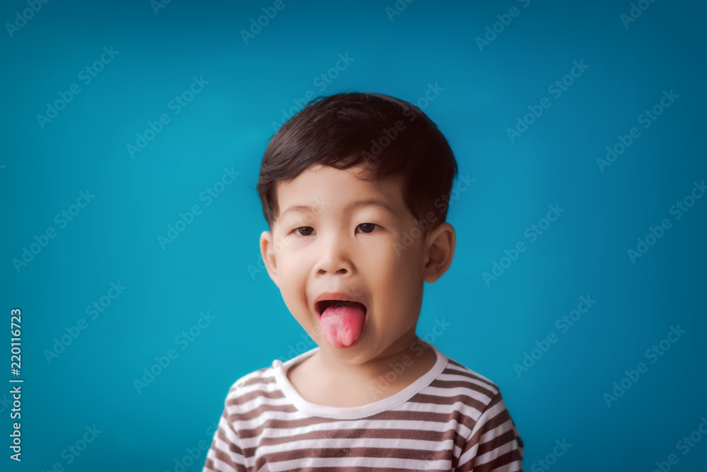 Child having fun and tongue out against blue background.