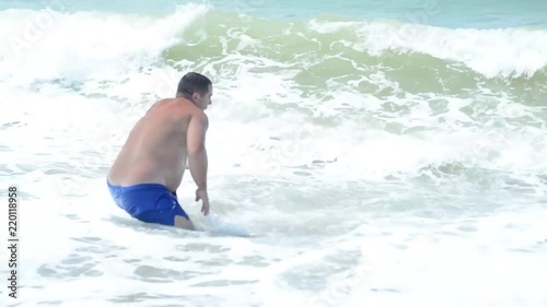 Fat guy on the beach, having fun with the waves. The concept of a fun vacation at sea.