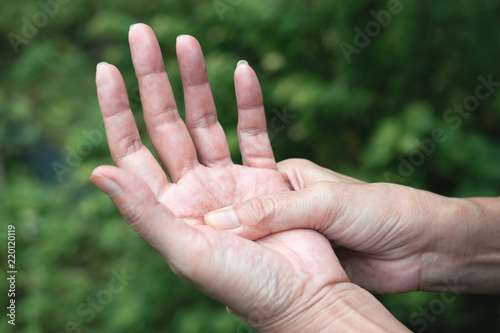 Closeup hand of person massage her hand from pain in healthy concept on nature background. © mintra